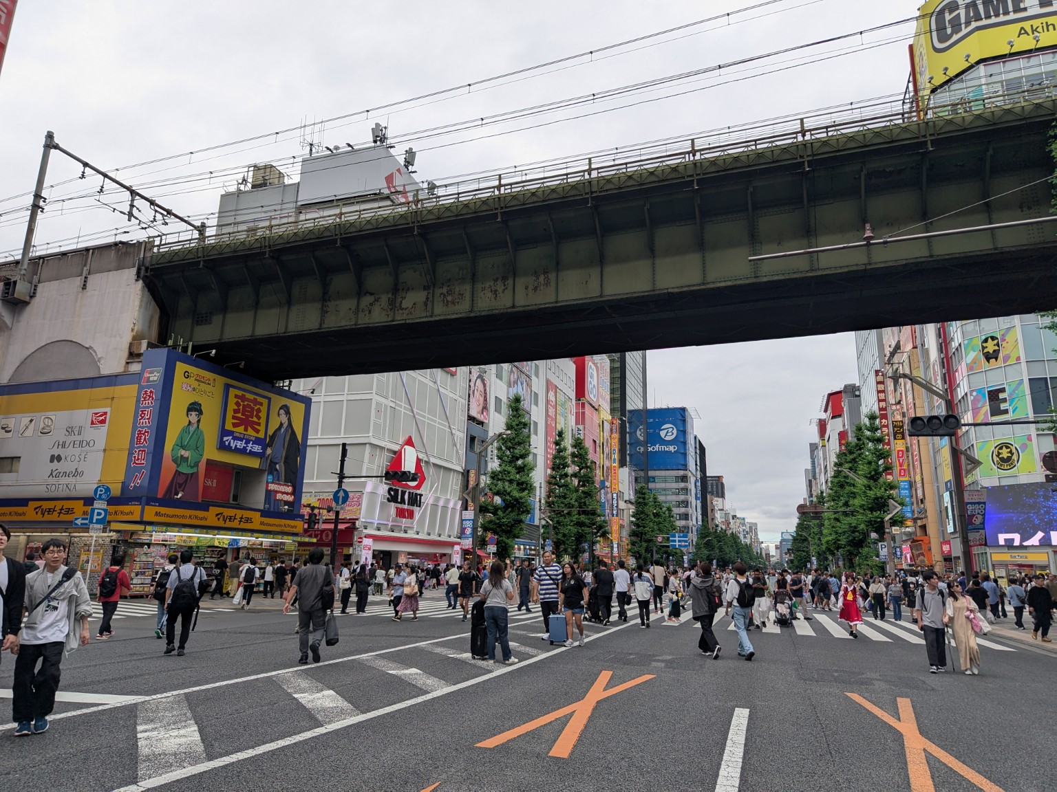 People walking along Chuo-dori beneath a railway bridge during pedestrian-only hours.
