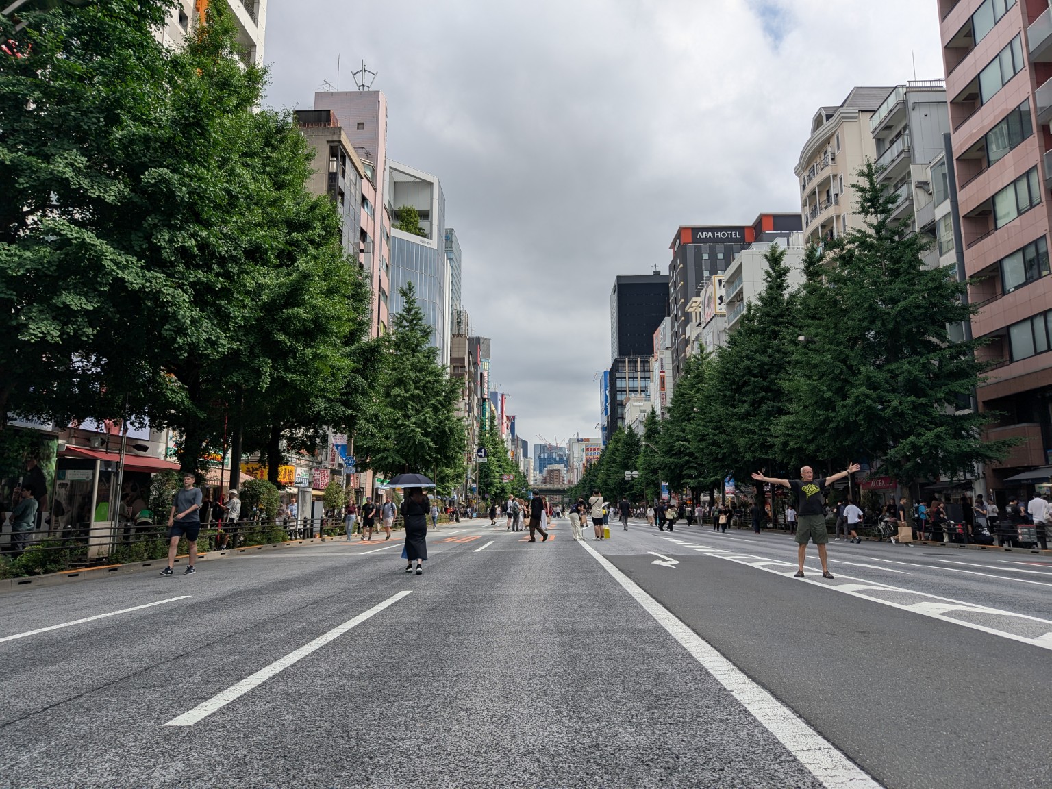 People walking on the roadway of Chuo-dori, with trees and buildings on both sides.